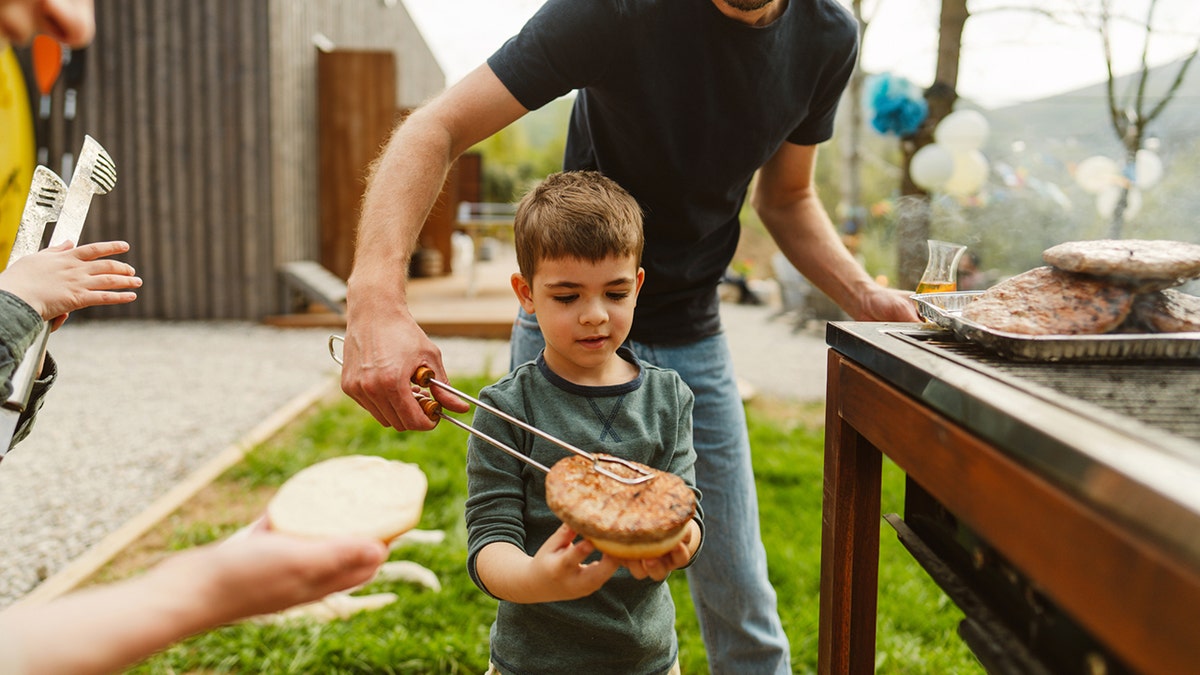 family preparing burgers connected  the grill