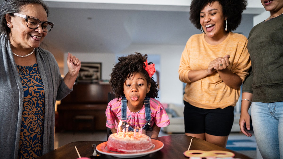 Niña soplando las velas de su tarta de cumpleaños