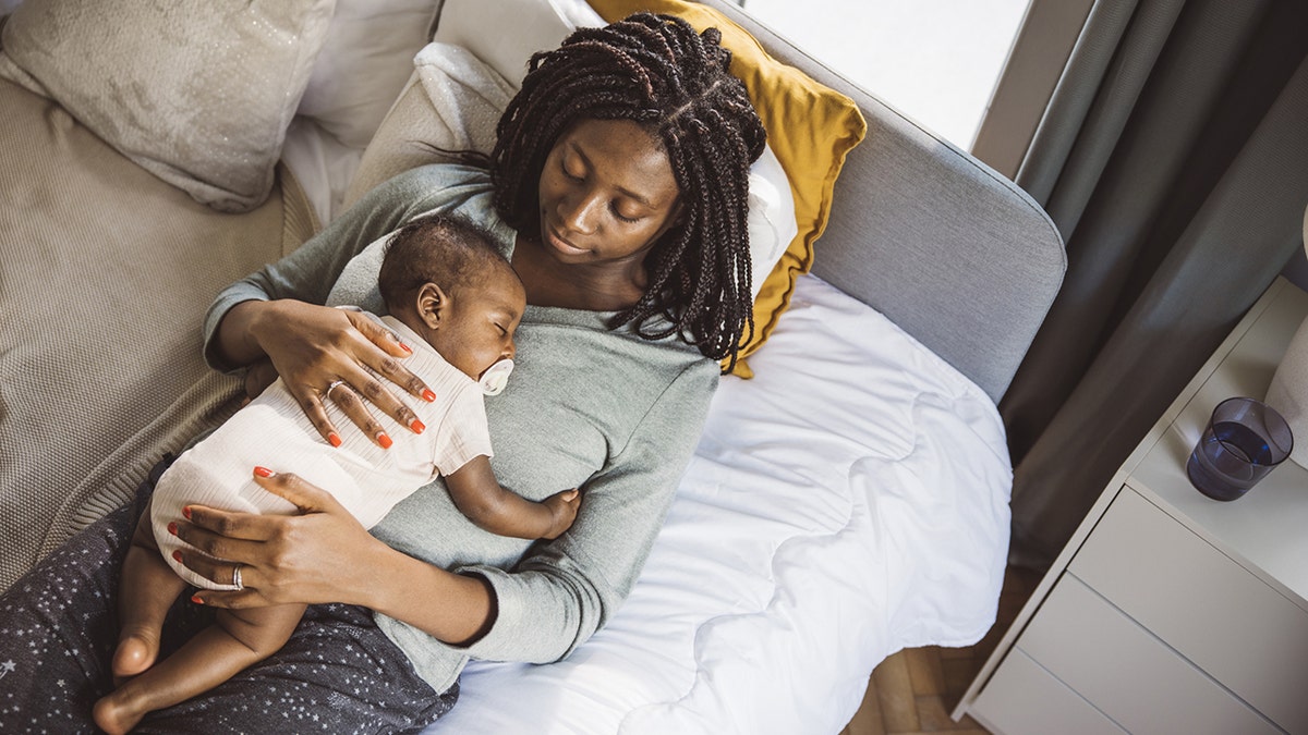 Young mother holding baby while he asleep