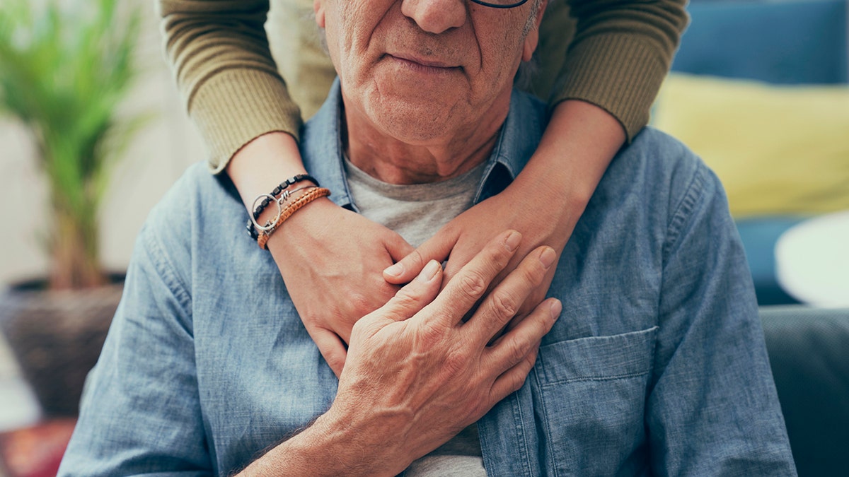 Mano consoladora sobre el hombro del hombre