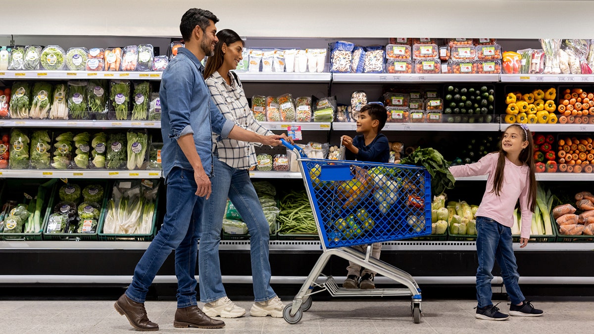 Family uses a shopping cart while buying groceries in the supermarket