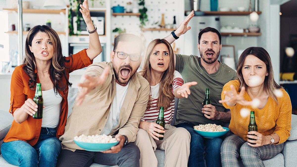 Grupo de amigos reunidos en casa para ver la tele y comer bocadillos