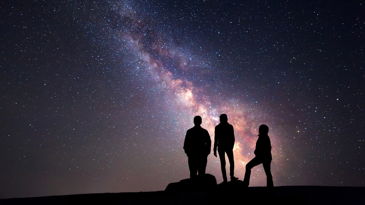 Cielo nocturno y silueta de una familia