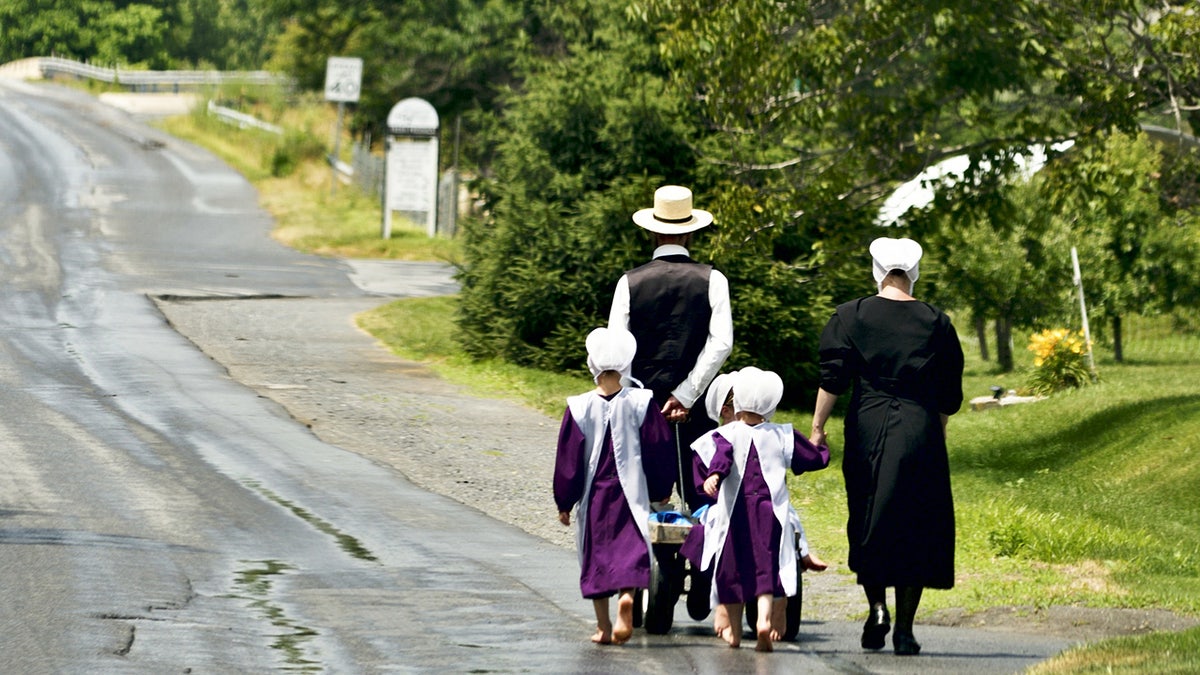 Família Amish andando em trajes tradicionais Amish. Seus rostos não são mostrados.