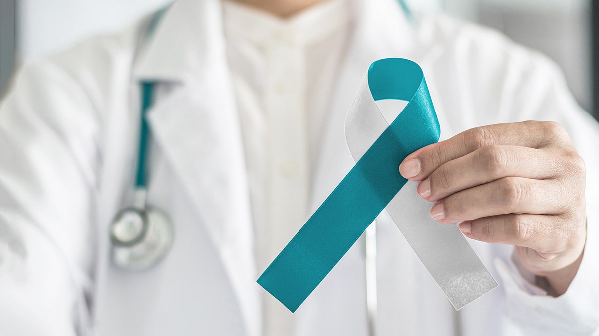 doctor holds teal and achromatic ribbon for Cervical Cancer awareness