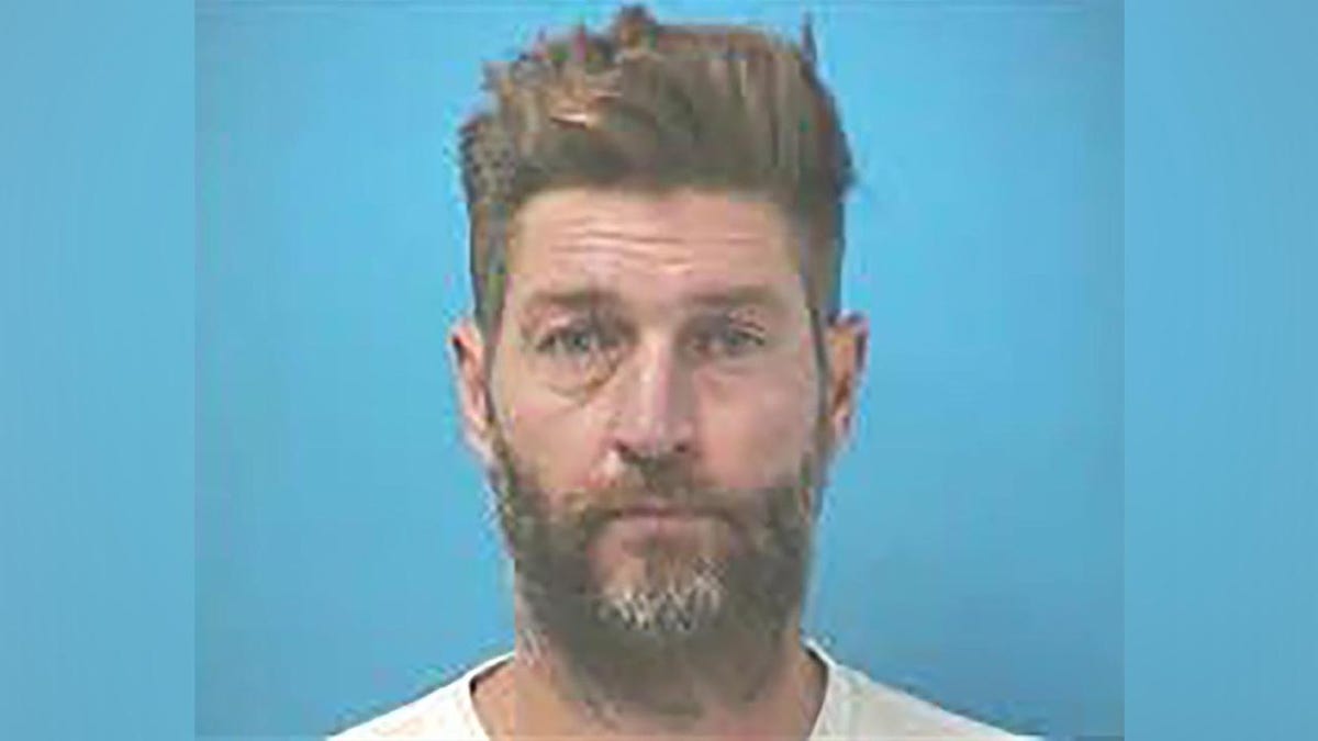 Jay Cutler with a scruffy beard does not grin  for his mugshot