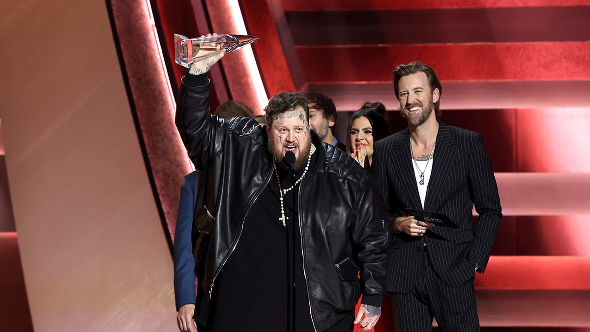 Jelly Roll holds up the CMA award before dropping it