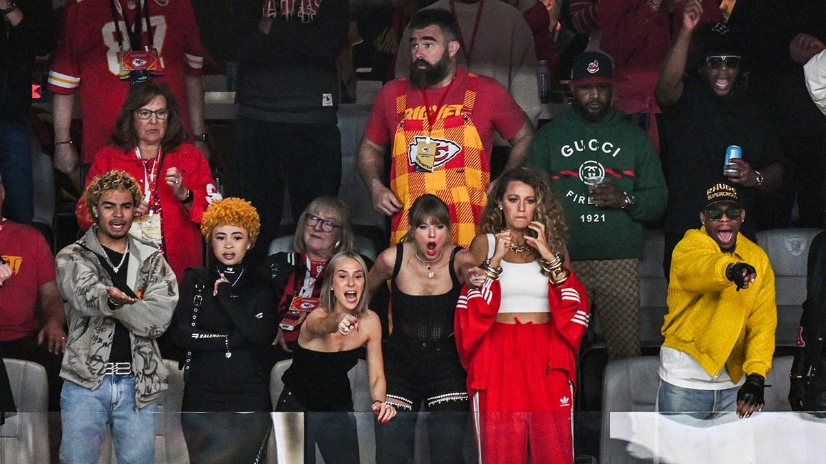 Taylor Swift wears black in a box with friends during the Super Bowl with Jason Kelce standing behind her in Chiefs gear