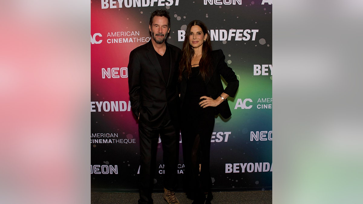 Keanu Reeves and Sandra Bullock, some  successful  achromatic  outfits, clasp  onto each   different   connected  the carpet