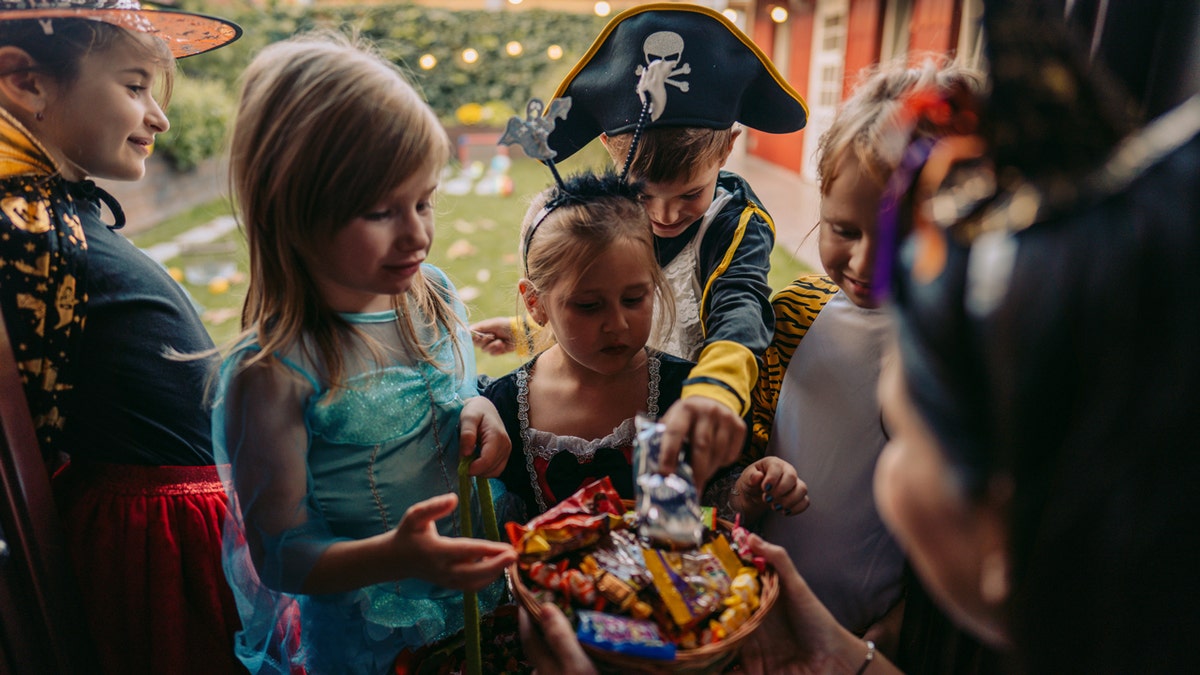 Children choose from a bowl of candy at a Halloween party.