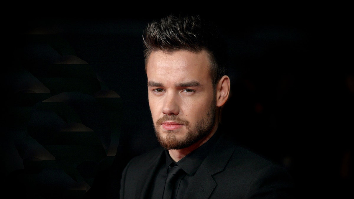 Singer Liam Payne wears black suit with black shirt.