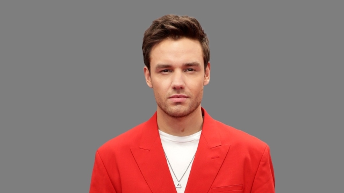 Liam Payne wears a red blazer in a portrait.