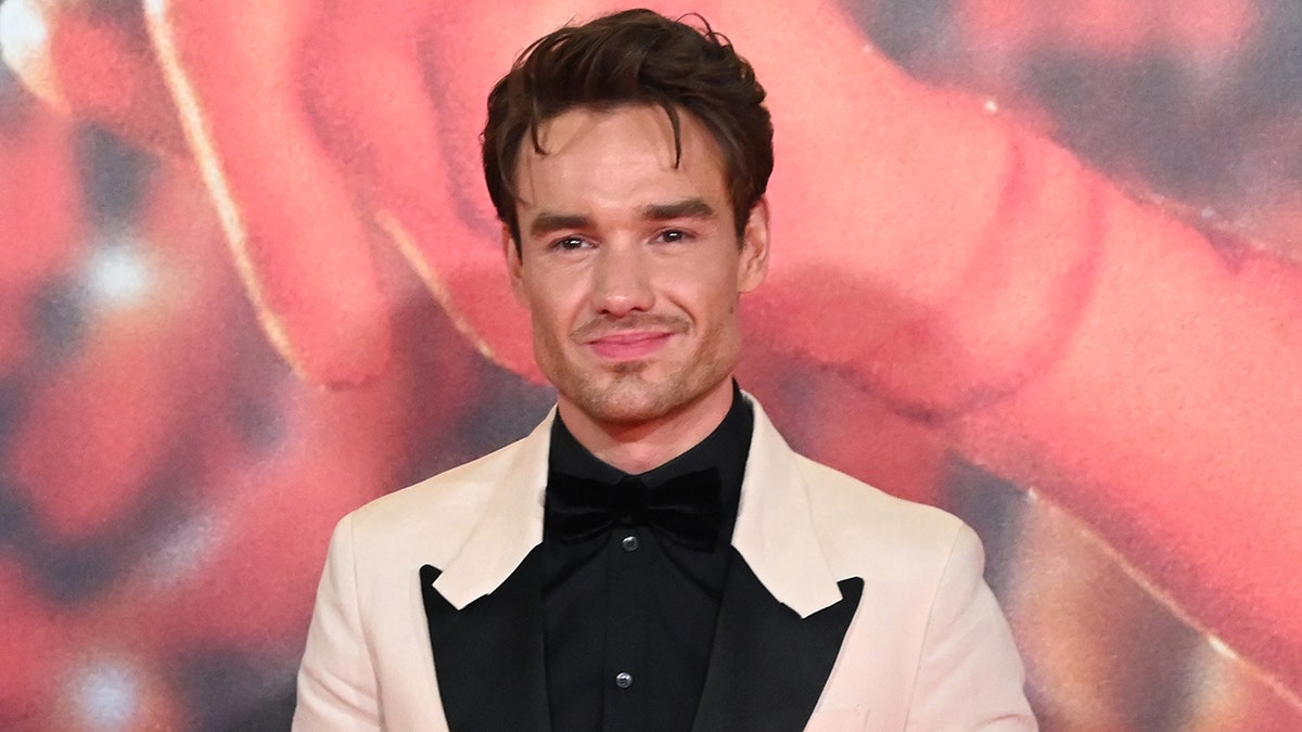 Liam Payne mengenakan jas putih dengan kemeja hitam.