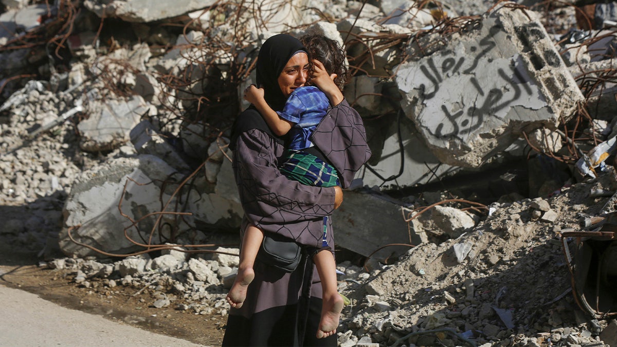 Una mujer palestina sostiene a su hijo en brazos y llora frente a un edificio derrumbado mientras los cuerpos de los palestinos muertos en un ataque israelí al campo de refugiados de Burez son llevados al hospital Al-Awda en la ciudad de Gaza para su entierro. 19, 2024.