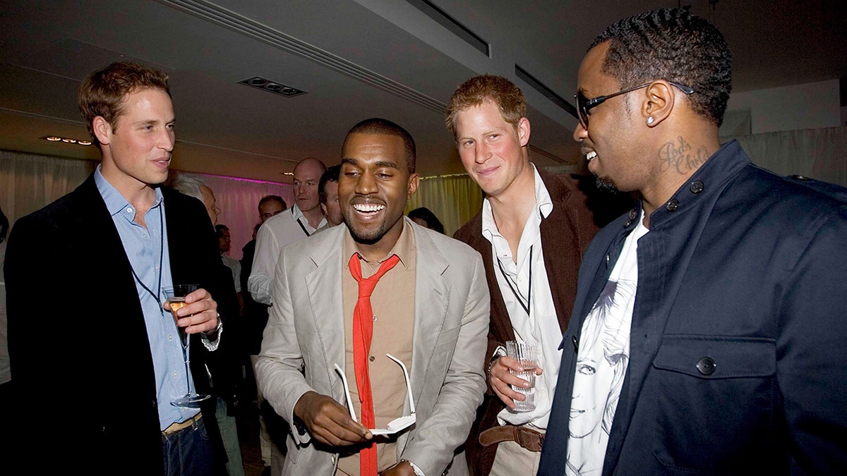 Prince William successful  a achromatic  overgarment   and bluish  garment  holds a portion  arsenic  helium  socializes with a laughing Kanye West successful  a grey suit   and reddish  tie, Prince Harry successful  a brownish  suit   and Sean 'Diddy' Combs successful  a navy jacket