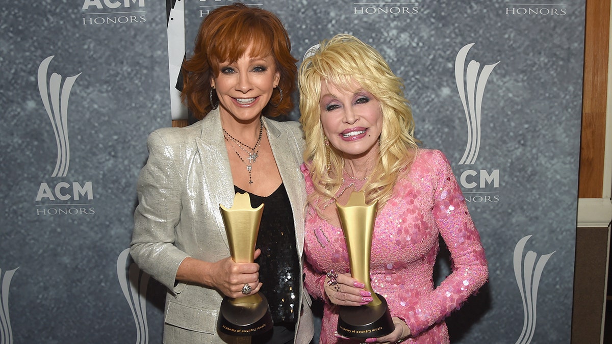 Reba McEntire in a gold glitter suit and black shirt holds an ACM Award, while Dolly Parton also receives an ACM Award in a bubblegum pink dress