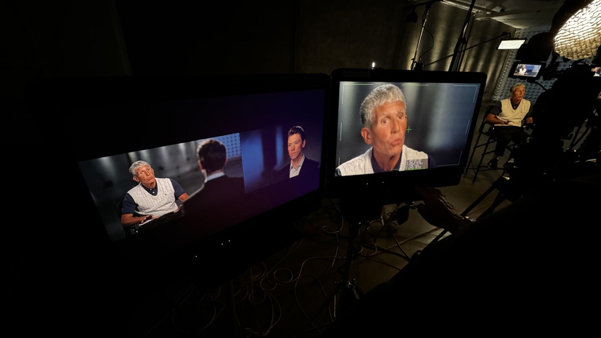 The monitors show Matt Finn sitting across from Rick Singer.