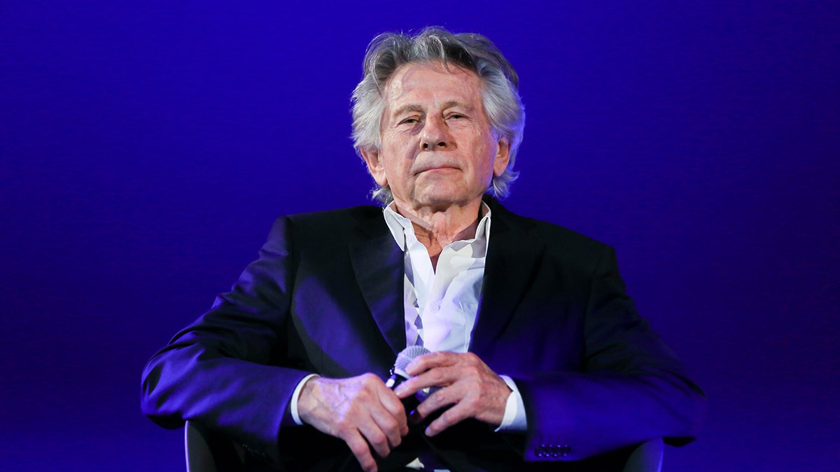 Director Roman Polanski wears white shirt and black blazer.