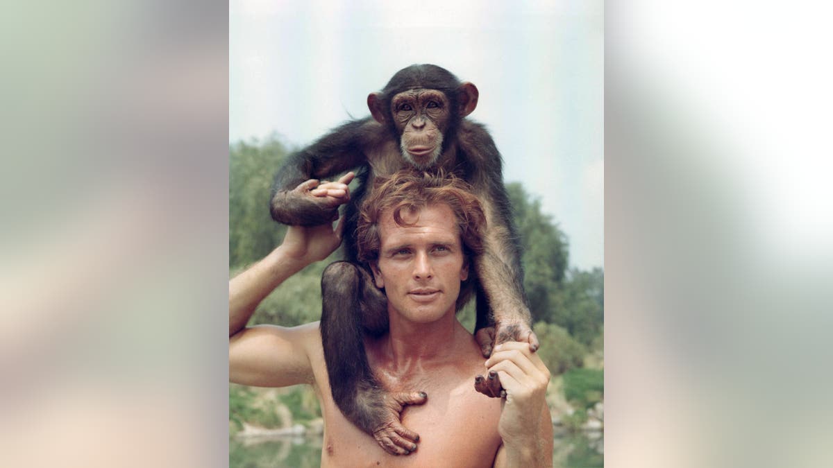 Ron Ely as Tarzan holding monkey on shoulders