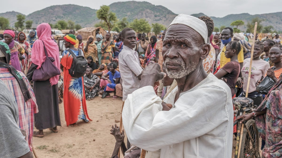 A crowd of people wait to receive food cards at the Agiri internal displacement camp, one of the first camps to open in the Nuba Mountains. June 2024.