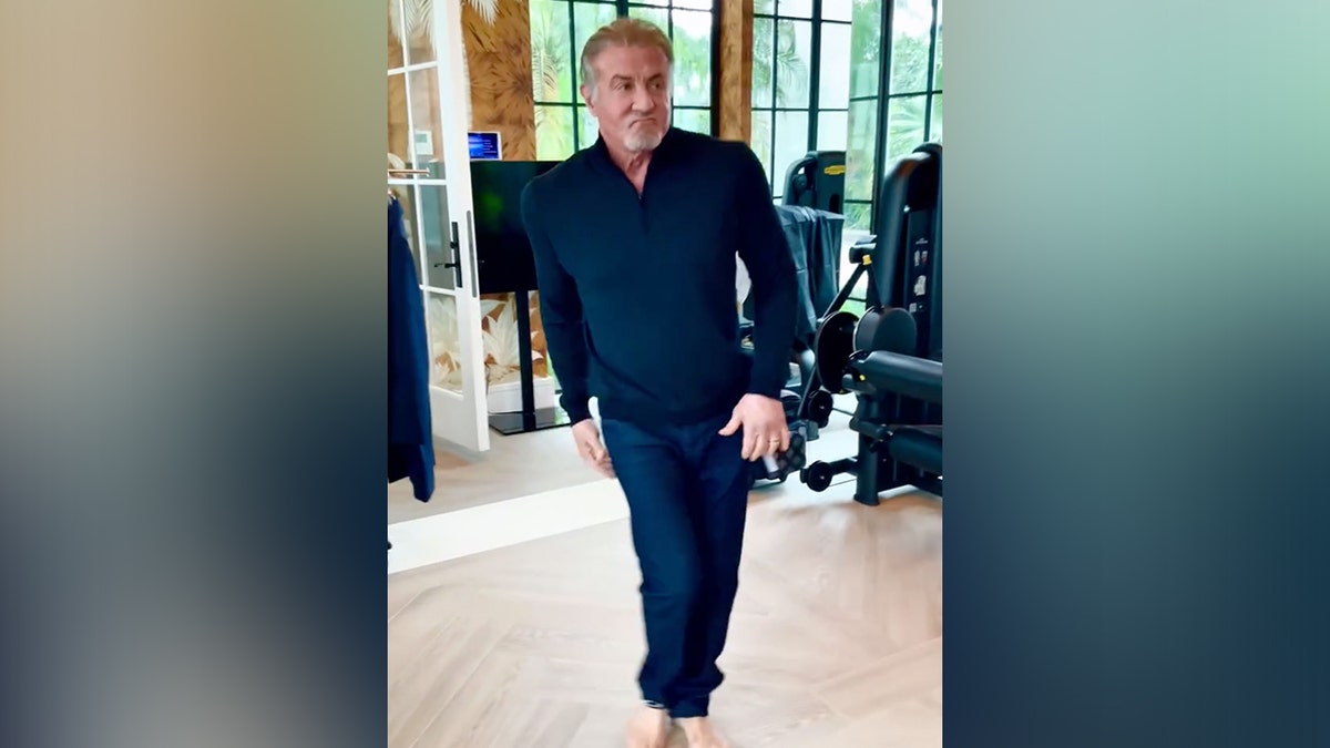 Sylvester Stallone in a blue shirt and blue pants dances during a fitting