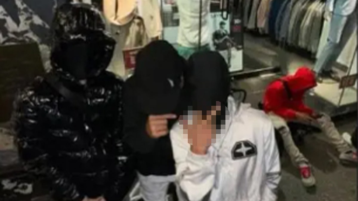 Suspected Tren de Aragua members with their faces covered make a rude gesture