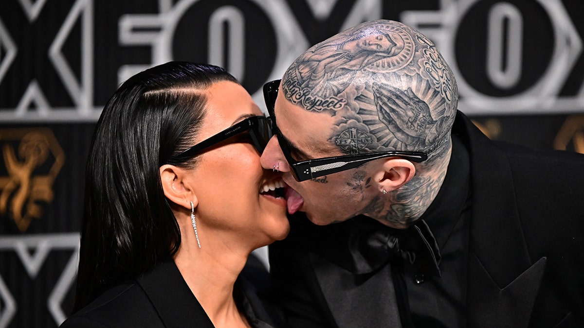 Travis Barker uses his tongue to kiss Kourtney Kardashian.