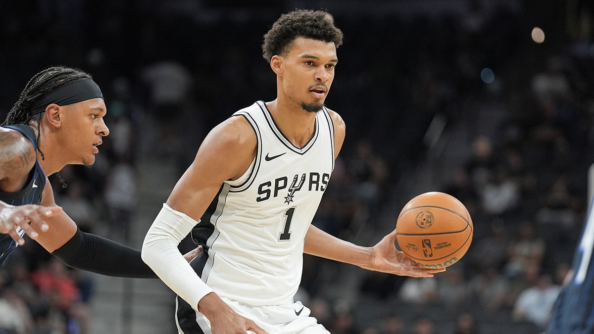 Oct 9, 2024; San Antonio, Texas, USA; ?San Antonio Spurs center Victor Wembanyama (1) handles the ball in front of Orlando Magic forward Paolo Banchero (5) in the first half at Frost Bank Center.