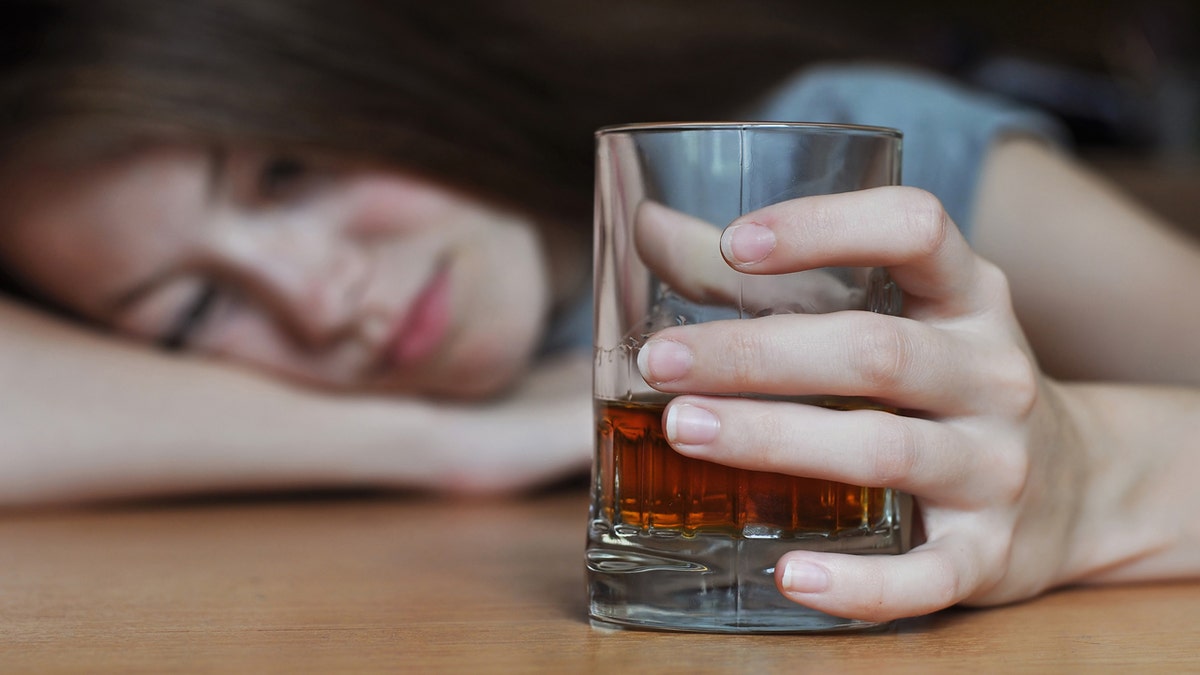 A seemingly drunk woman holding a glass of alcohol 