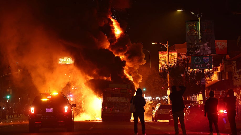 People watch a bus burn