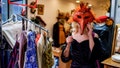 A woman explores a selection of unique and colorful vintage items in a second-hand store. She examines a vibrant, feathered Venetian-style mask with intrigue, appreciating the eclectic and artistic atmosphere of the shop. Thrifting and vintage shopping offer her a chance to discover one-of-a-kind pieces with history and character, while embracing sustainable fashion choices. - Fox News