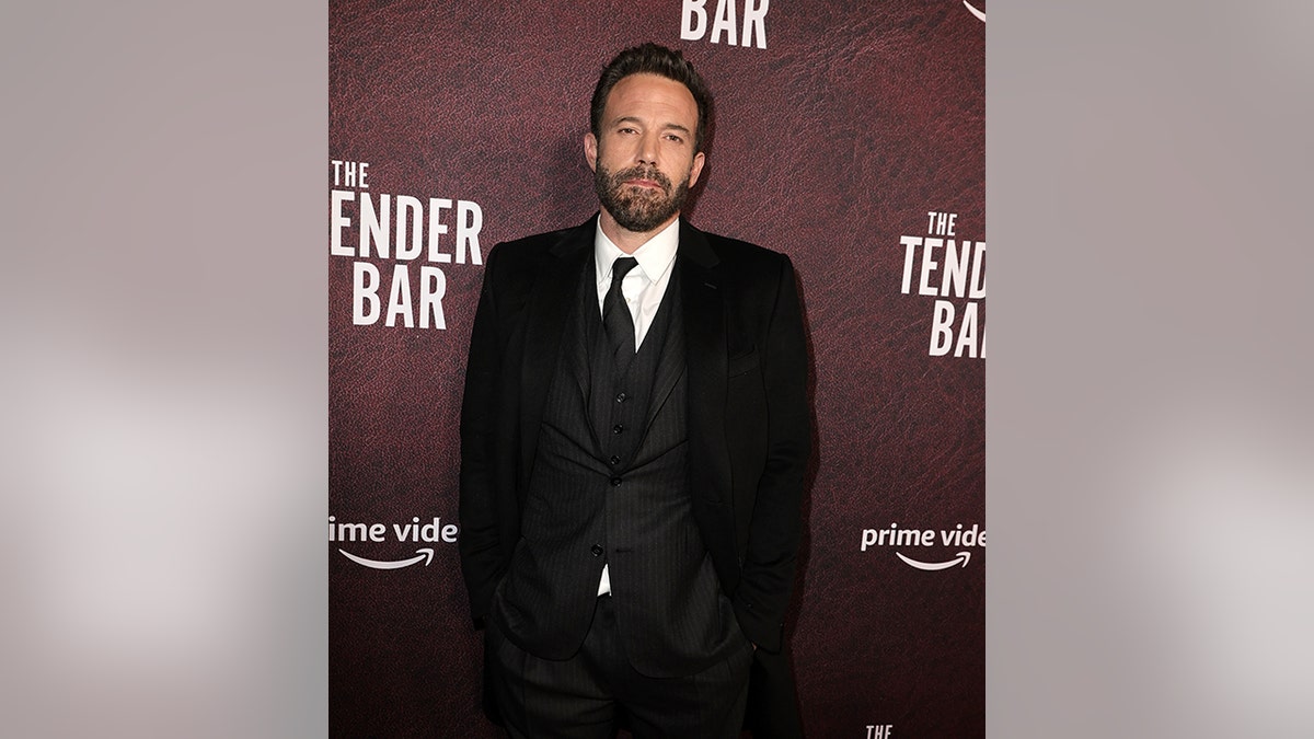 Ben Affleck in a three=-piece black suit and black tie looks serious on the carpet