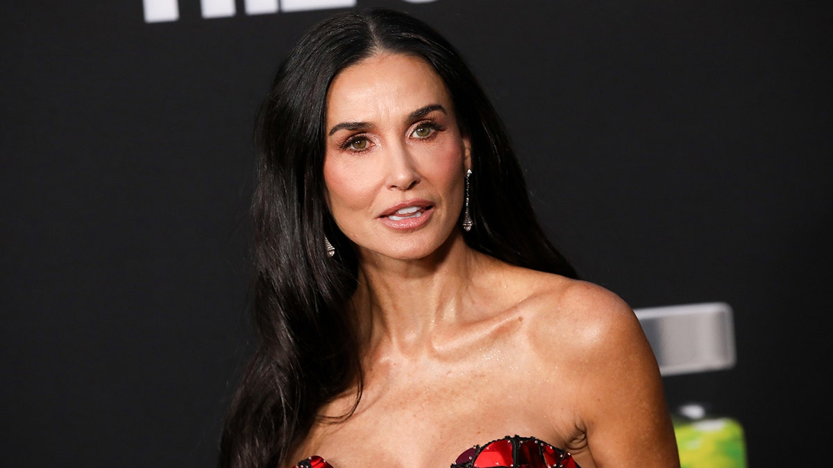 Demi Moore mira ligeramente a su izquierda con un vestido rojo y negro sin tirantes en el estreno de "The Substance" en Los Ángeles