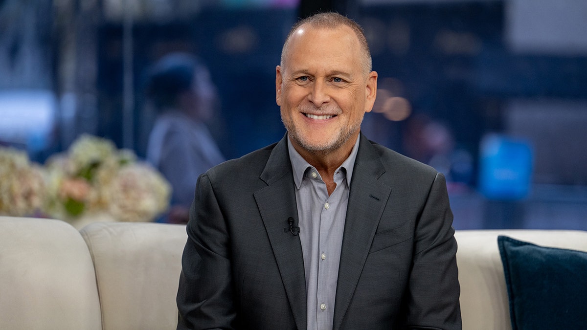 Dave Coulier in a dark grey suit smiles on "TODAY" with a partially bald head