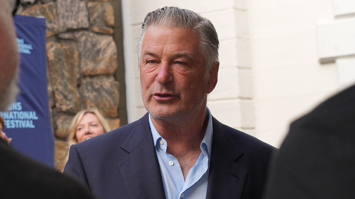 Alec Baldwin, con una camisa azul abotonada y un traje azul marino, es fotografiado en un acto en Nueva York