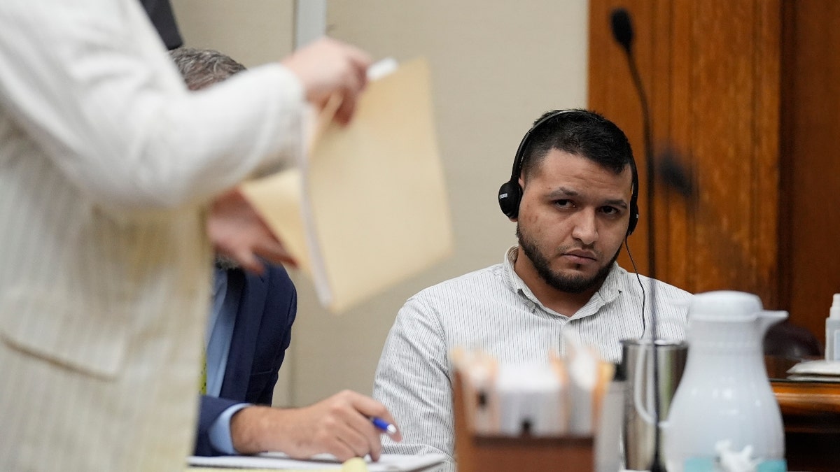 Defense attorneys Kaitlyn Beck shuffles papers in a folder as Jose Ibarra, center, accused of killing a nursing student, Laken Hope Riley, appears in court for a motion hearing on Friday, Oct. 11, 2024, in Athens, Ga.