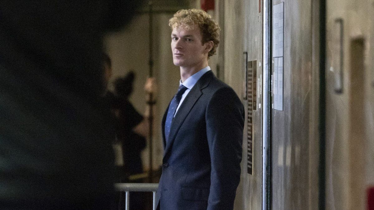 Daniel Penny arrives at the court weating a navy blue suit with curly blonde hair