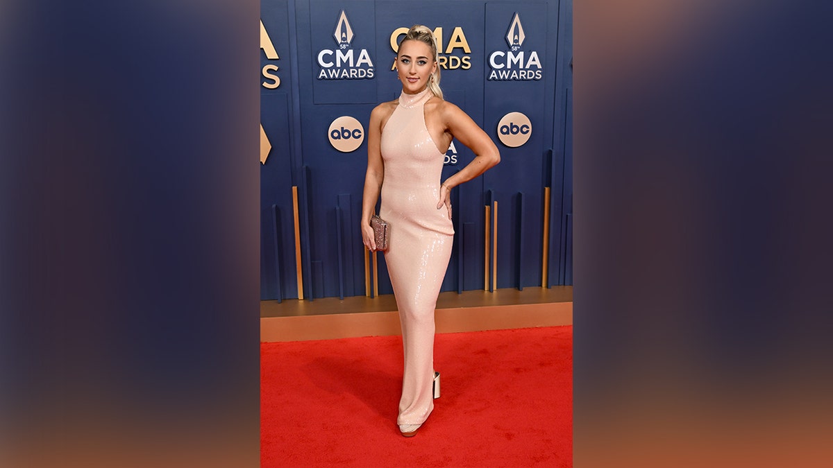 Ashley Cooke wore a light pink gown with a halter neckline on the 2024 CMA Awards red carpet.