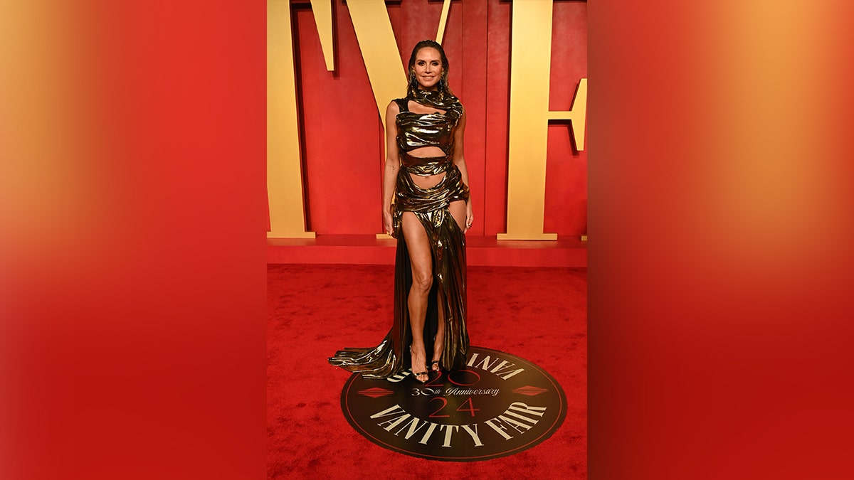 Heidi Klum mengenakan gaun emas dengan banyak potongan dan celah ke pesta Vanity Fair Oscar