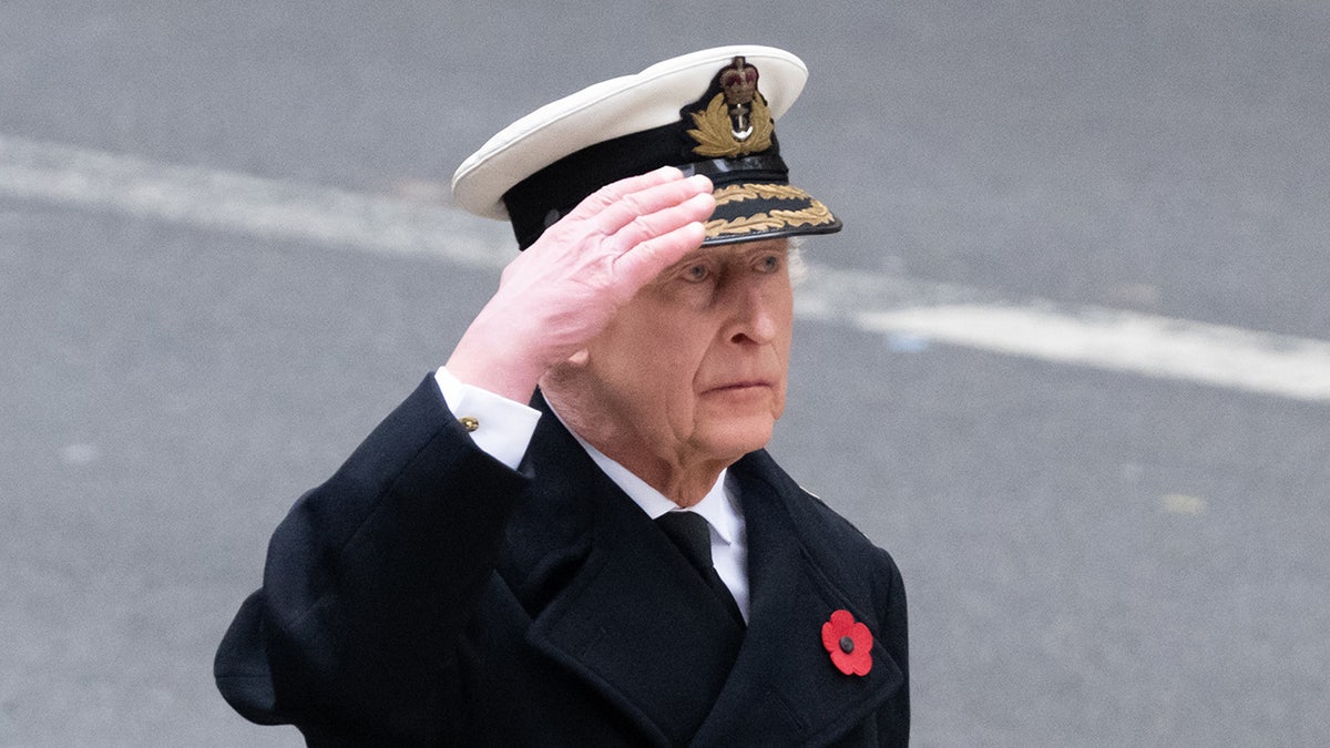 King Charles saluting and looking somber.