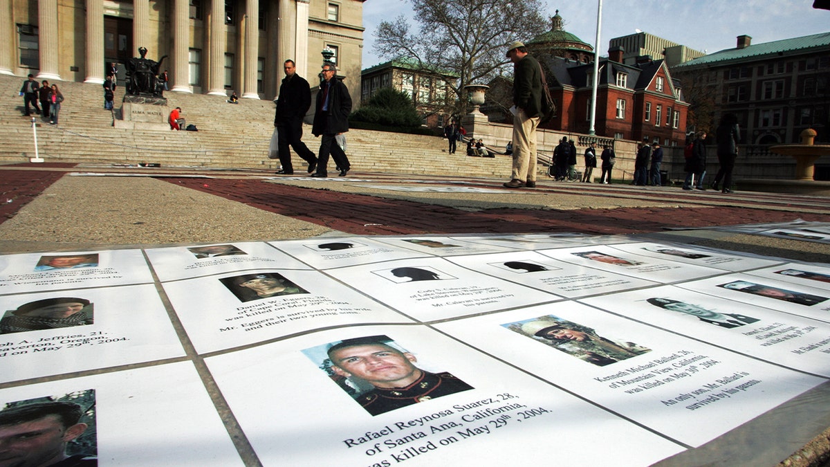 El Día de los Veteranos, un monumento conmemorativo con nombres y fotos de estadounidenses muertos en las guerras de Afganistán e Irak es contemplado por los transeúntes en la Universidad de Columbia.