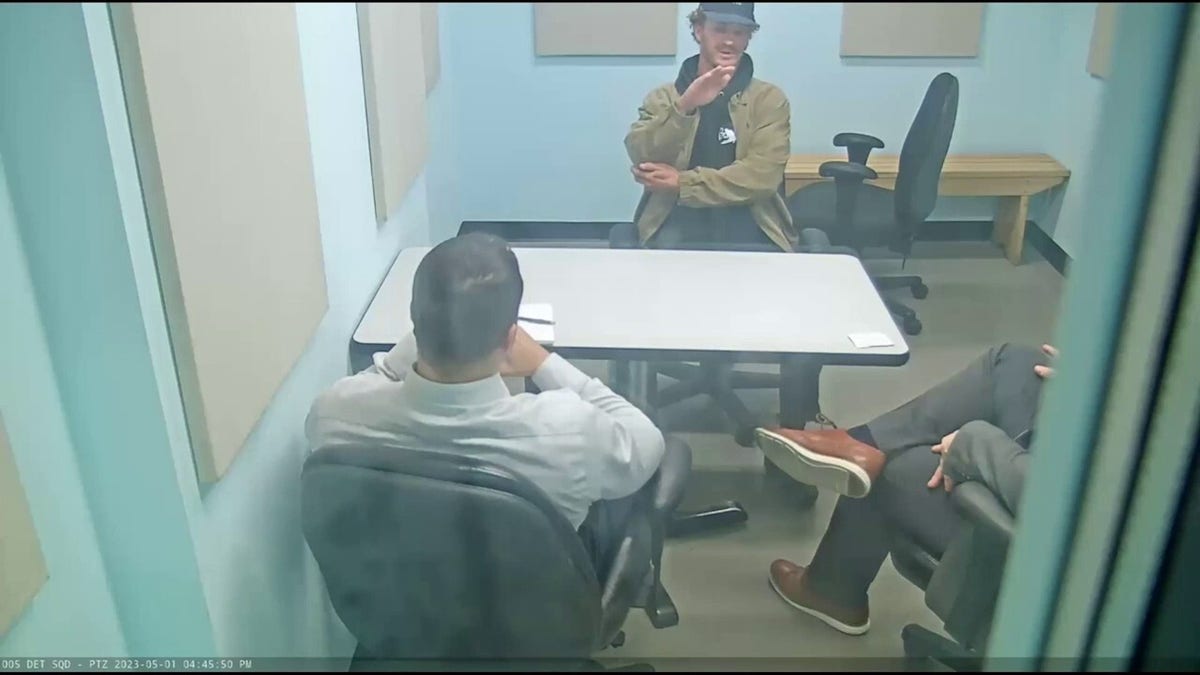 Penny puts his hand near his mouth as he speaks with two NYPD detectives