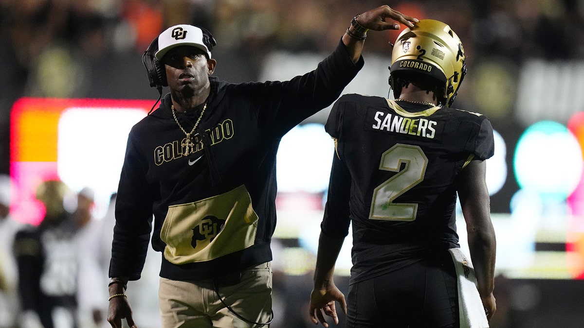 Deion Sanders pats Shedeur Sanders on helmet