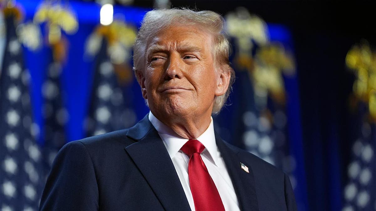 Donald Trump smiling in a navy suit and red tie