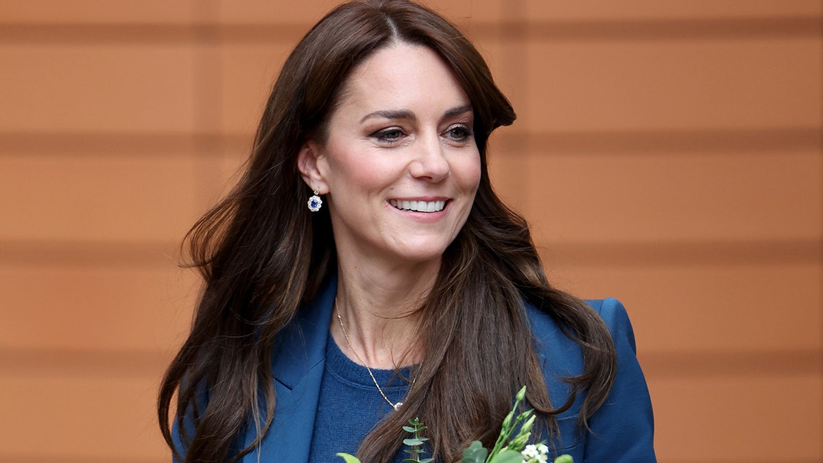 Kate Middleton wearing a blue suit holding flowers.