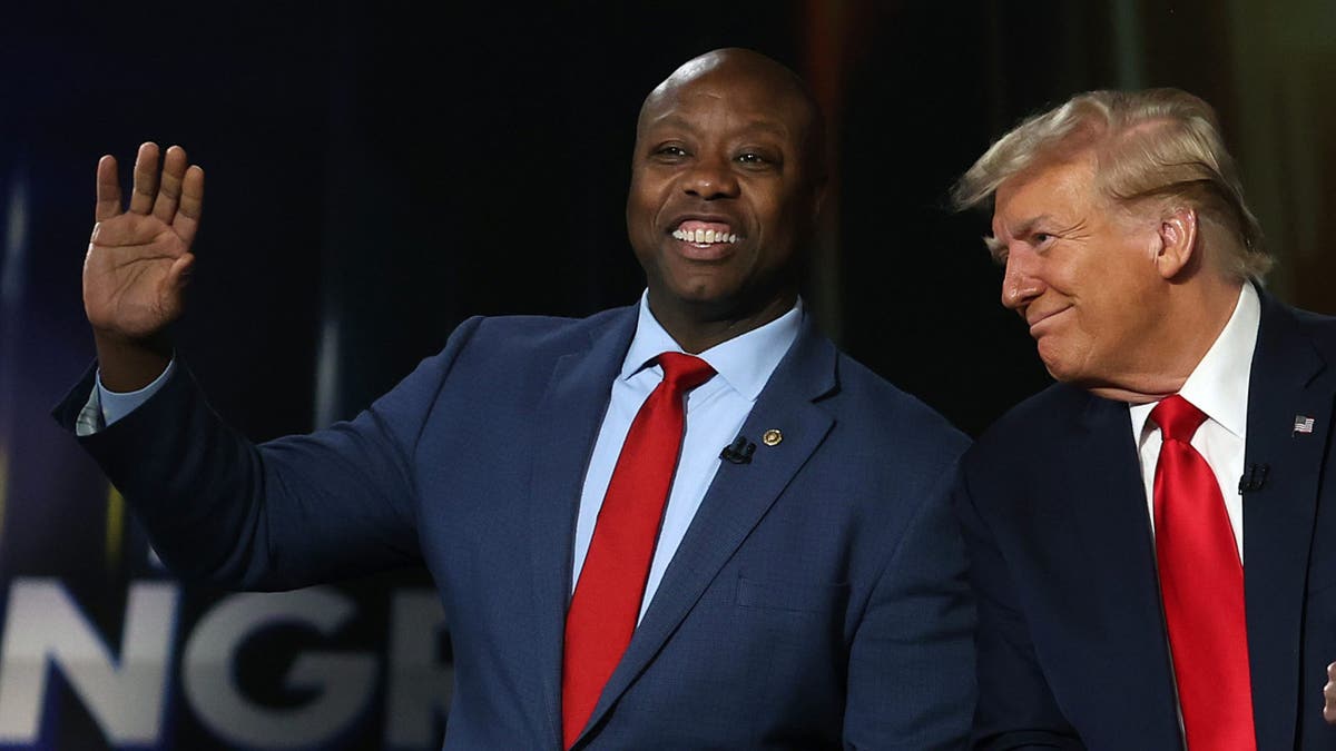 Tim Scott waves with Trump next to him at South Carolina campaign stop