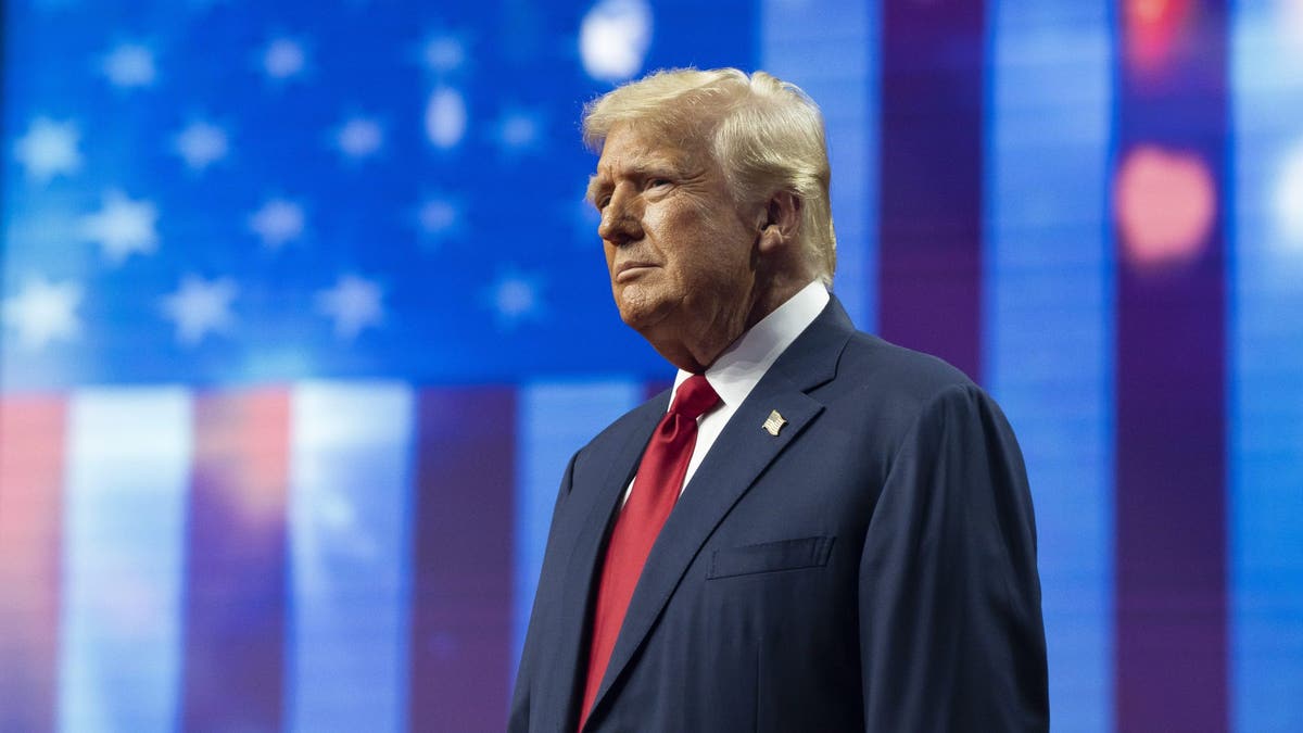 Trump on stage in front of a large American flag