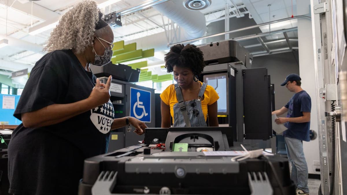 Two women stand near the voting machine