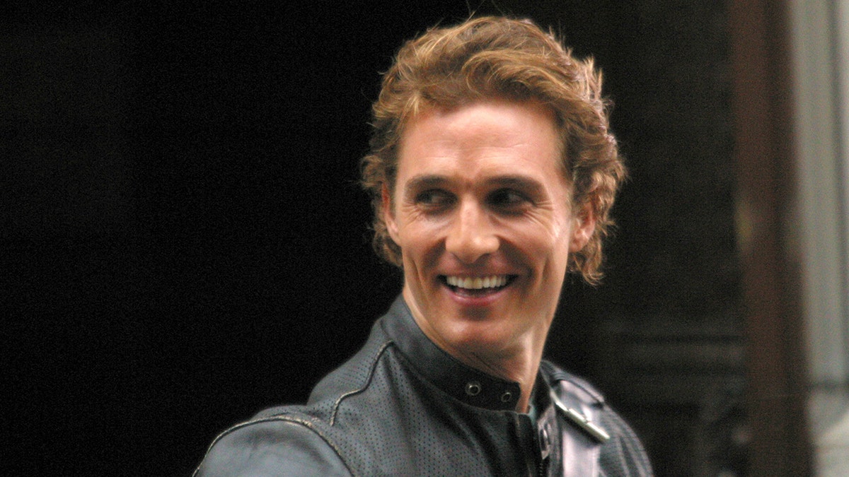 Matthew McConaughey smiles and looks over his shoulder wearing a leather jacket on the set of "How to Lose a Guy In 10 Days"