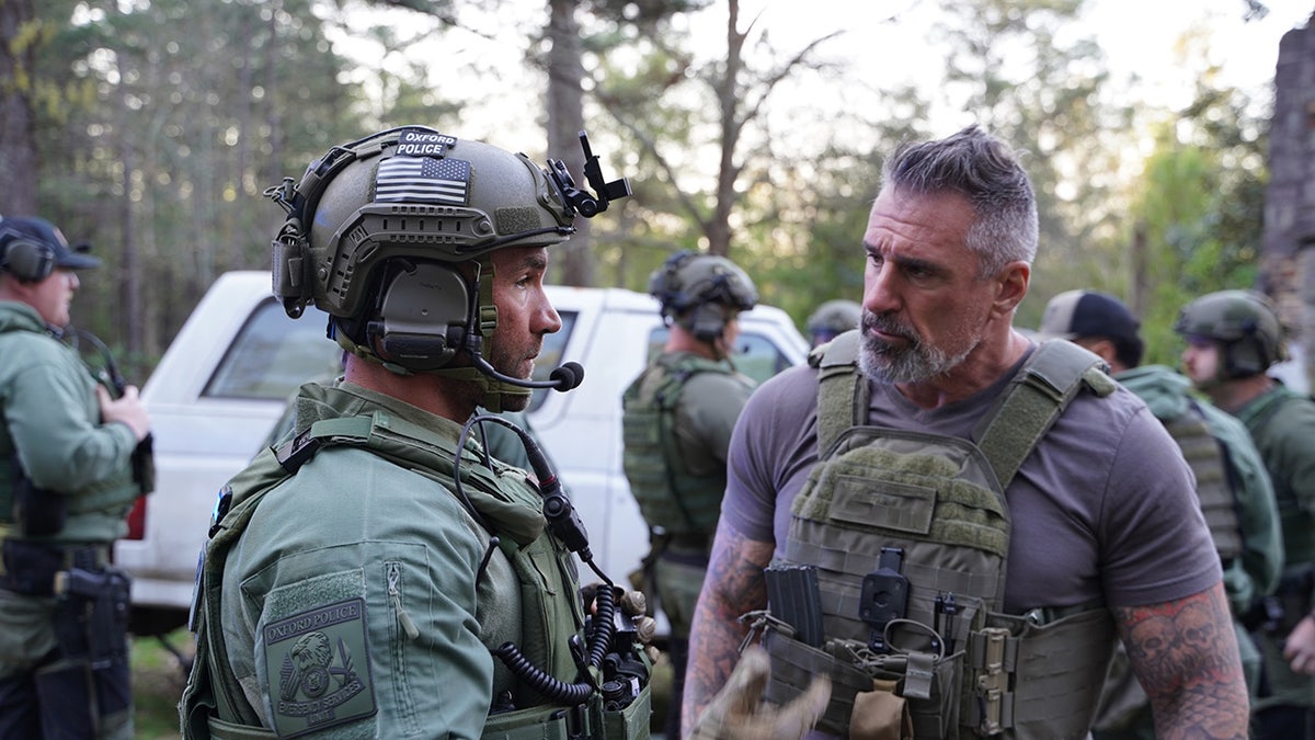 Lou Valouze hablando con un agente de uniforme.